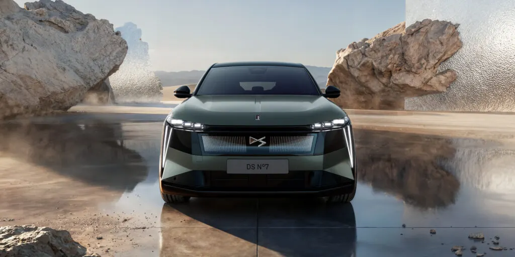 DS N°7 vue de devant avec sa calandre et ses phares allumés dans un décor avec de la roche et du soleil