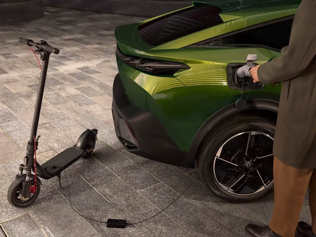 Homme qui recharge la Nouvelle pugeot 408 avec la trotinette qui recharge