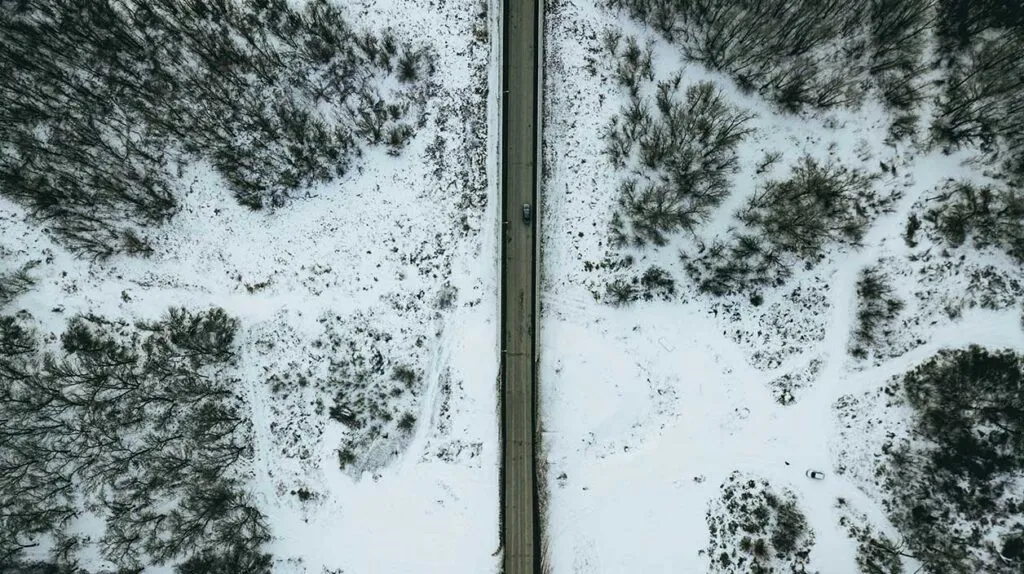 Une route enneigée avec une voiture qui a surement un bon équipement