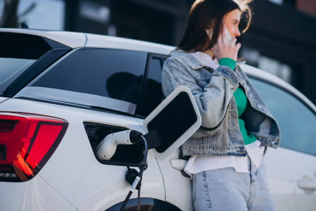 Une femme qui téléphone en attendant que sa voiture charge