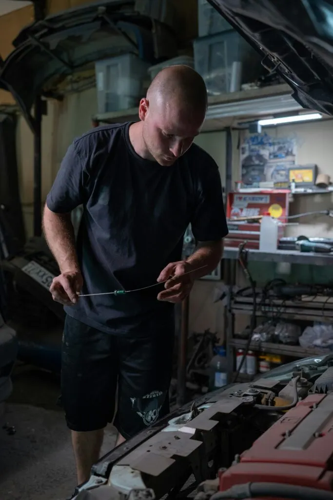 Un mécanicien dans un garage qui utilise une jauge à huile sur un moteur de voiture