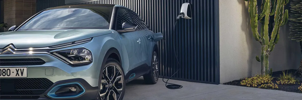 Photo d'une voiture électrique devant le garage d'une maison