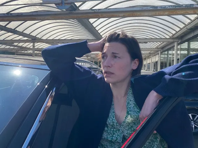 femme paniquée avec son véhicule sûrement en panne parce que certains de ses voyants voitures sont allumés