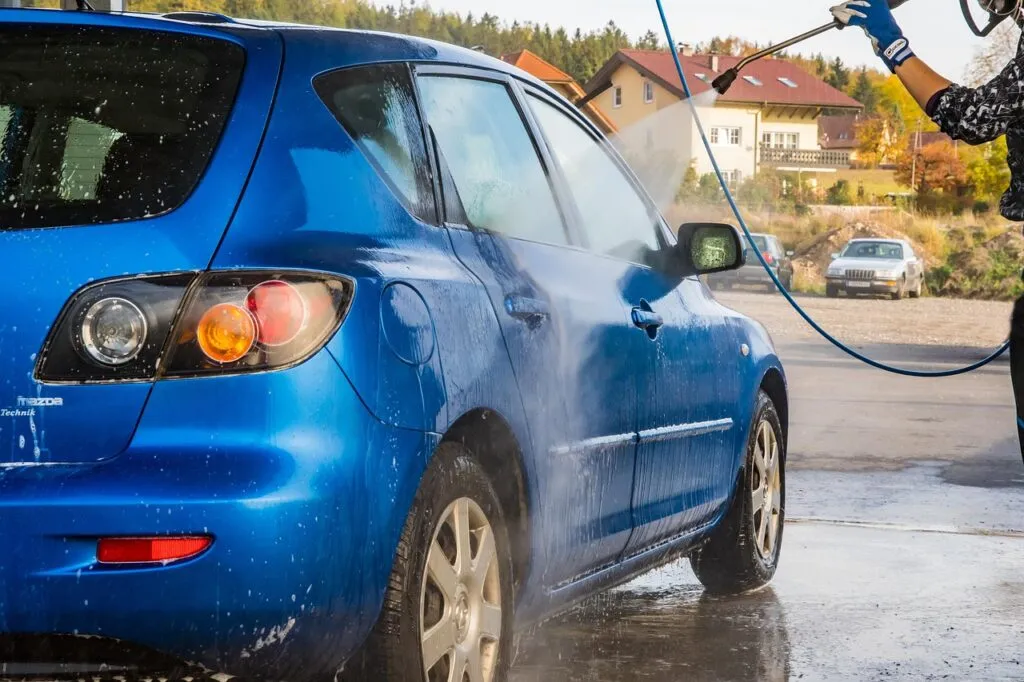Homme qui lave sa voiture dans un lavomatique.