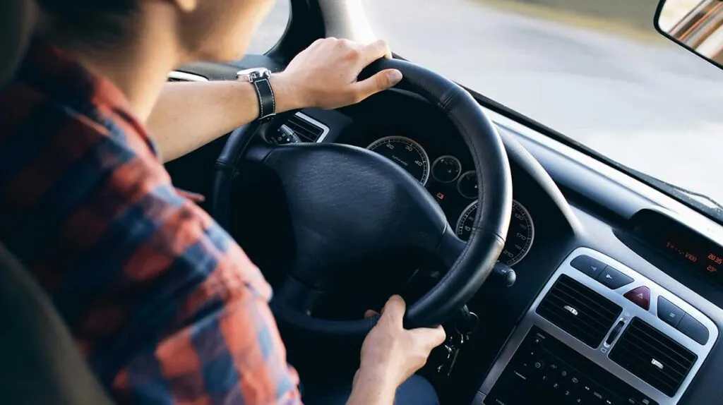 Un homme qui conduit les mains sur le volant