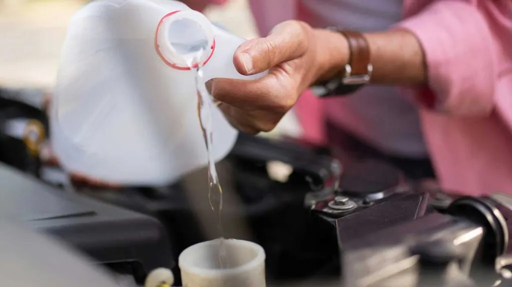 Un homme verse du liquide de frein dans un moteur de voiture