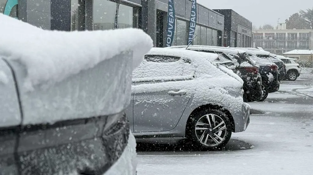 Des voitures garées dans un parc automobile sous la neige