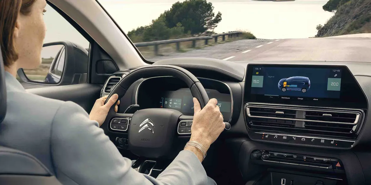 Femme qui conduit dans une voiture hybride Citroën sur la route