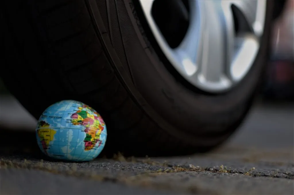 Pneu d'une voiture qui écrase une balle en forme de planète Terre