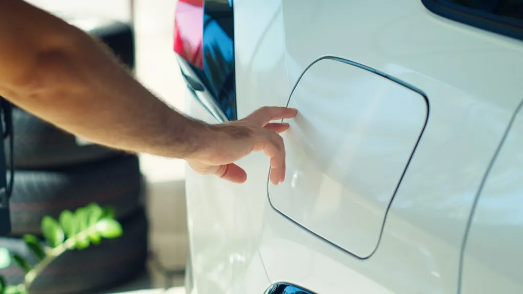 Un homme ouvre une trappe de recharge d'une voiture électrique