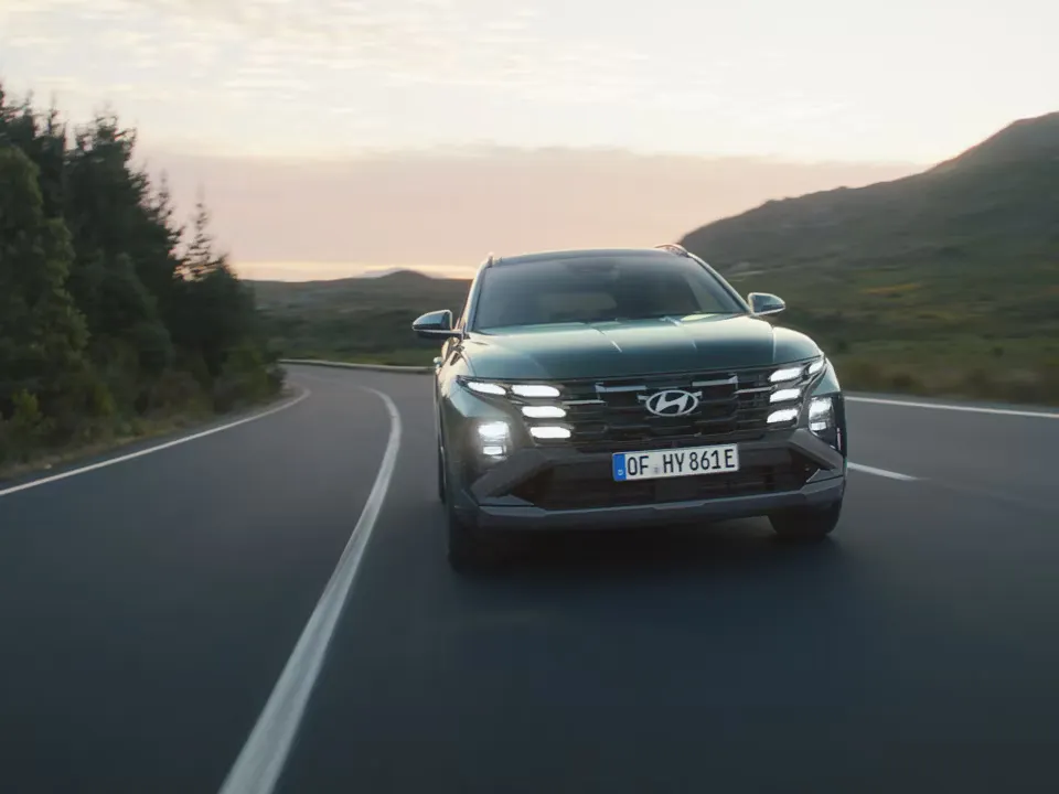 Hyundai Tucson sur la route avec les phares allumés