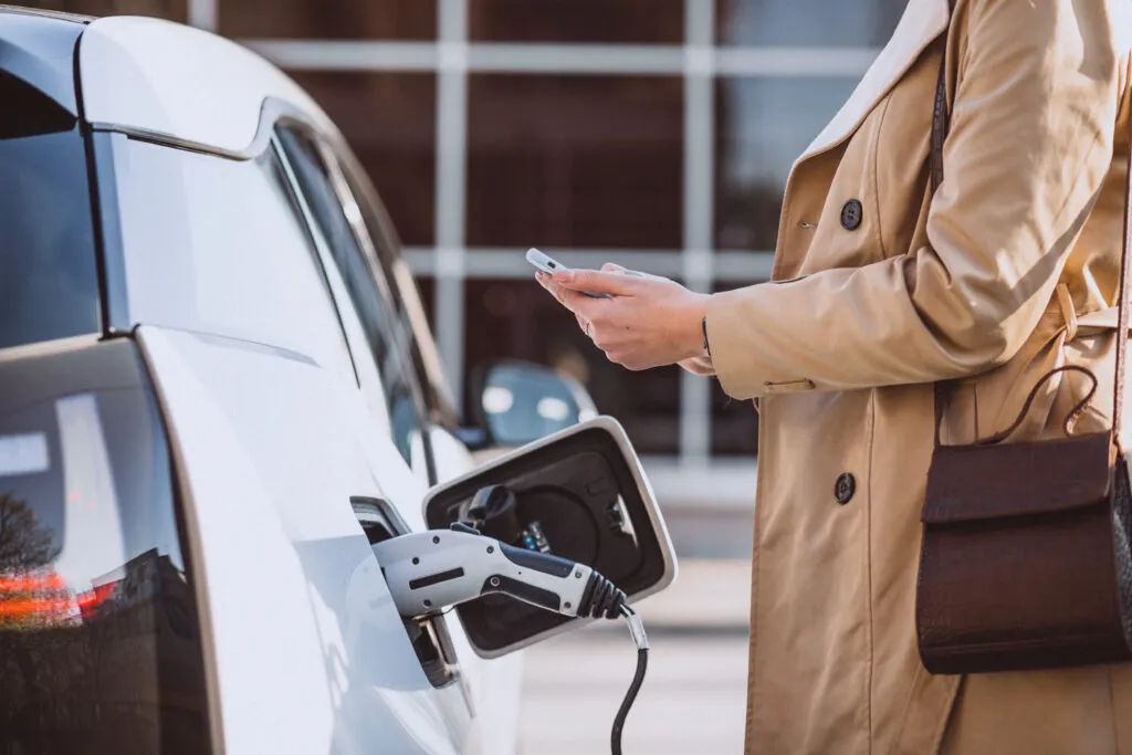 Une femme paye la recharge de sa voiture électrique alors qu'elle recharge via son téléphone portable