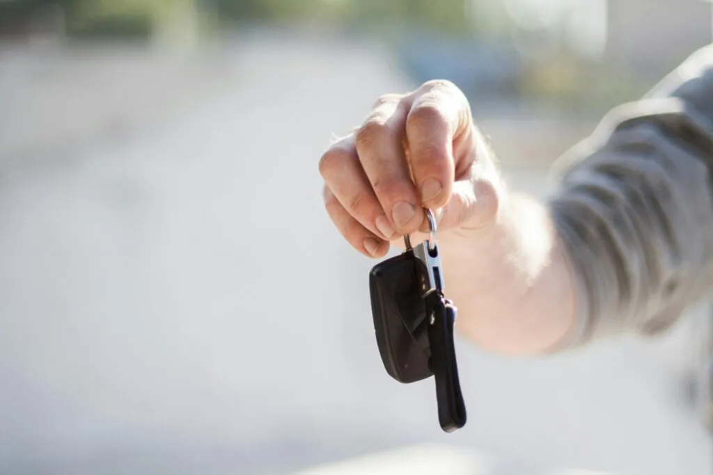 Un homme qui tend ses clés au concessionnaire parce qu'il a vendu sa voiture