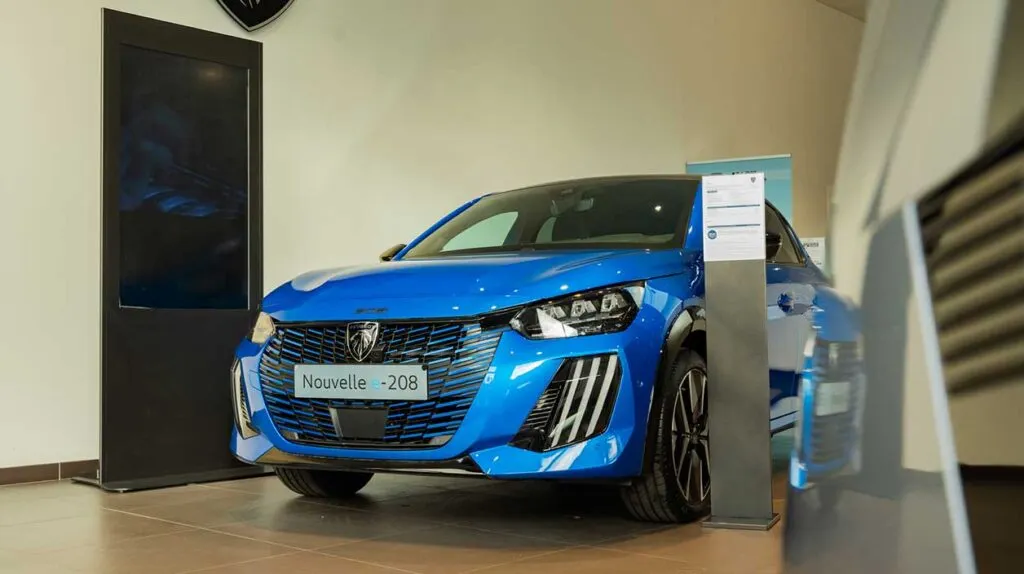 Une peugeot e-208 vue entièrement dans une concession automobiles de Mary Automobiles
