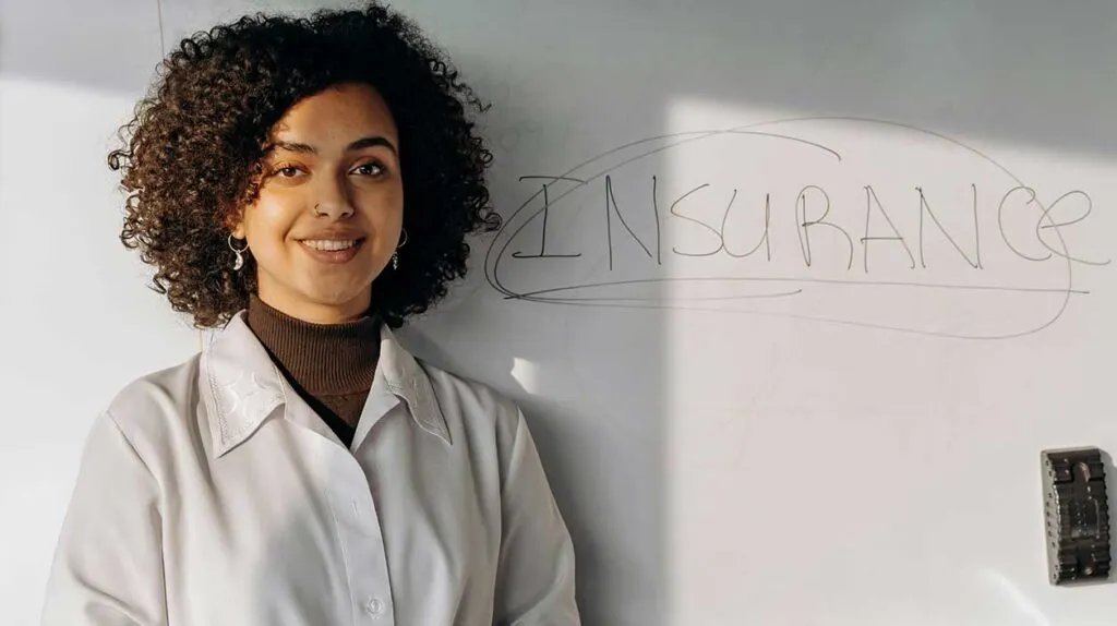 Une femme qui a écrit assurance en anglais sur un tableau