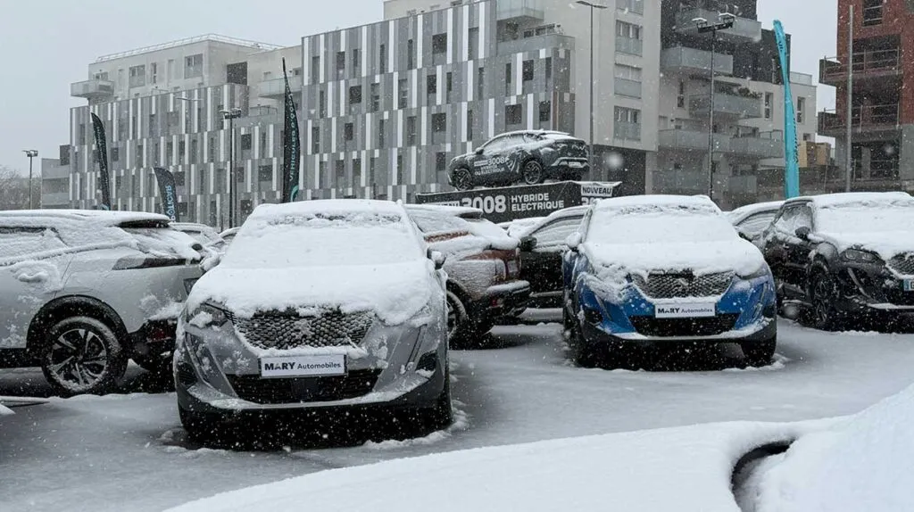 Plusieurs voitures garées dans le parc automobile d'une concession enneigée