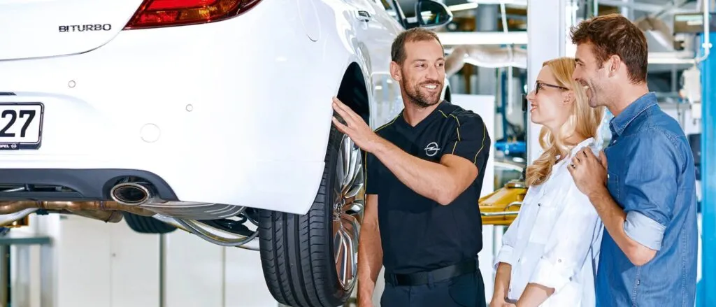 Après-vente deux Monsieur discutent et l'un so'ccupent d'une roue de voiture