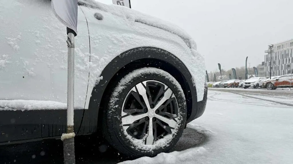 Détail d'une voiture : une roue sur une route enneigée