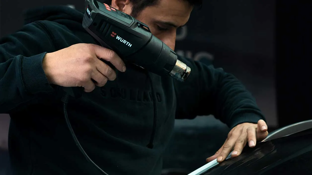 Un carrossier finit de remplacer un pare-brise