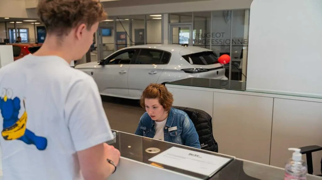Une secrétaire qui travaille dans une concession et qui aide un client