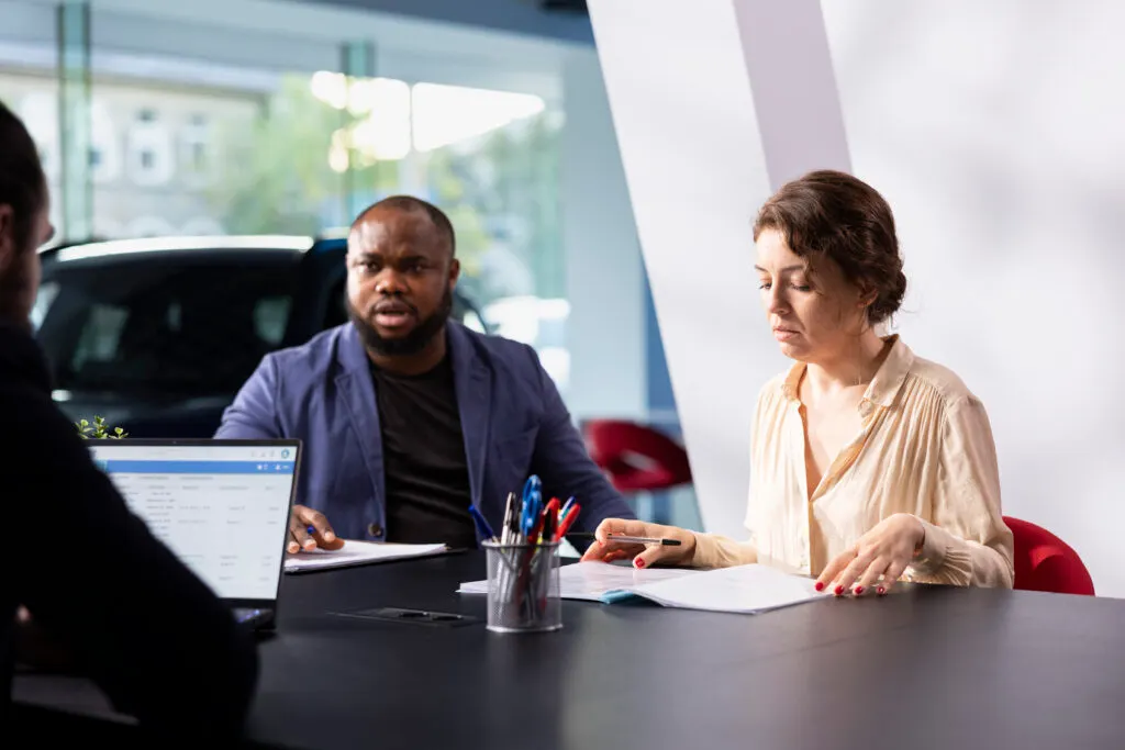 Un couple dans une concession automobile qui semble se poser des questions concernant la location sans apport d'une voiture