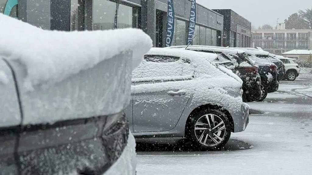 Des voitures garées dans un parc automobile sous la neige