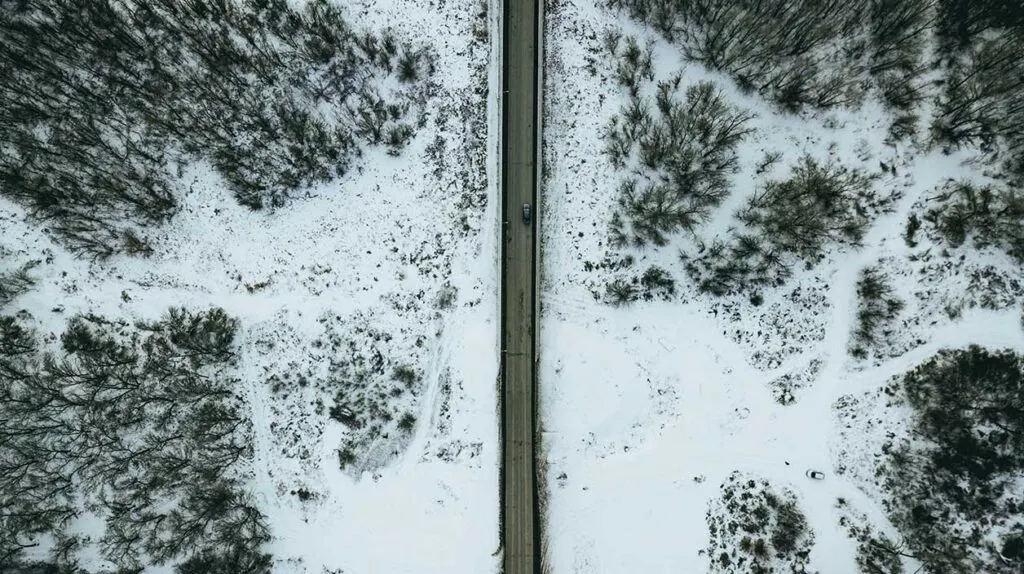 Une route enneigée avec une voiture qui a surement un bon équipement