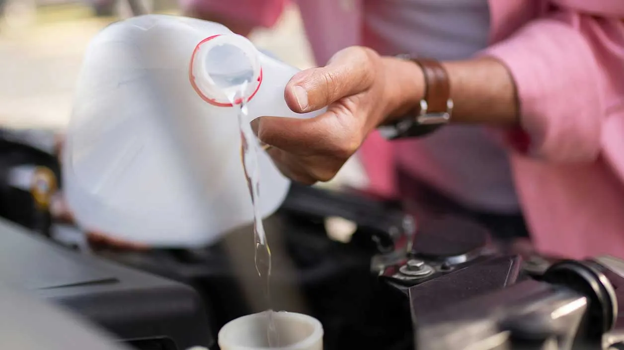 Un mécanicien vers du liquide de refroidissement dans le moteur
