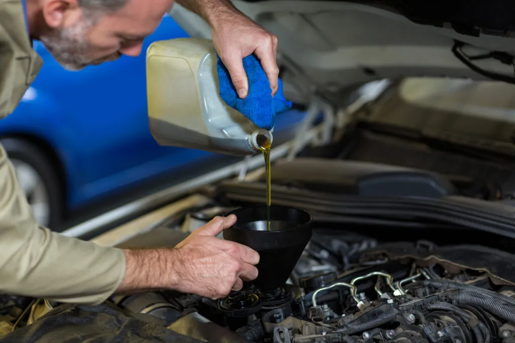Un homme qui met de l'huile dans un moteur