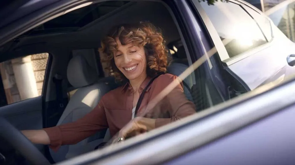 Une femme qui sourit dans sa voiture